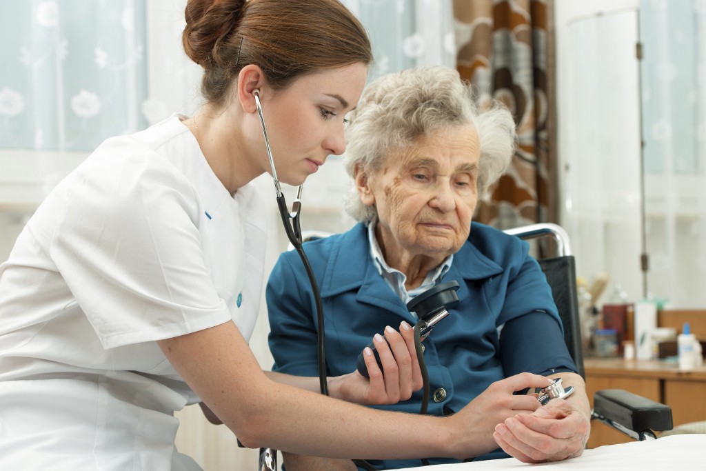 Female nurse measuring blood pressure of senior woman